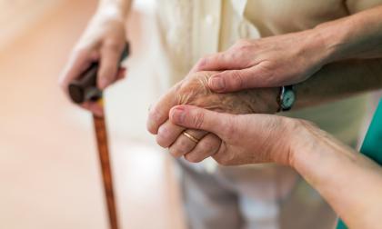 Nurse consoling her elderly patient by holding her hands