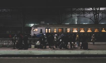 Lviv, Ukraine - March 4, 2022: People with luggage stand on a train station platform at night in Lviv, Ukraine