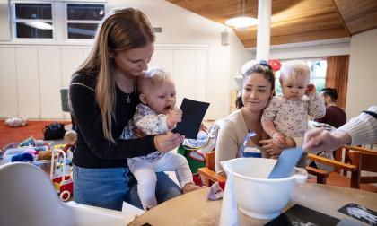 Vilja Karlsson i mamma Kaisa Väisänens famn tittar på sitt fotavtryck. Fanny Sjöblom med dottern Vera Sjöblom Salin ska också göra ett hand- eller fotavtryck.