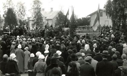 Högtidligheten då Mariehamns kyrkas grundsten lades den 4 september 1926. Mannen i den centralt placerade, flaggprydda talarstolen är biskop Max von Bondsdorff. Stadens kyrkoherde Erik Göransson ses i bildens vänstra kant, markerad med en vit pil. Han talade även vid ceremonin. 