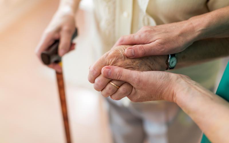 Nurse consoling her elderly patient by holding her hands