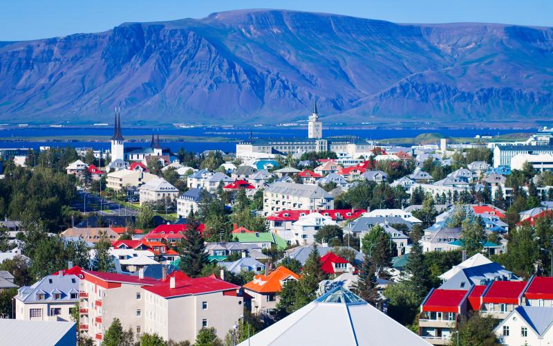 Beautiful summer super wide-angle aerial view of Reykjavik, Iceland with harbor and skyline mountains and scenery beyond the city, seen from the observation tower of hallgrimskirkja church with blue sky in sunny day.