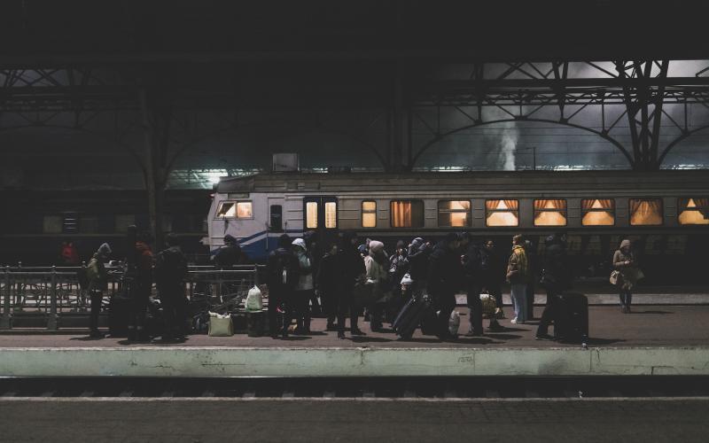 Lviv, Ukraine - March 4, 2022: People with luggage stand on a train station platform at night in Lviv, Ukraine