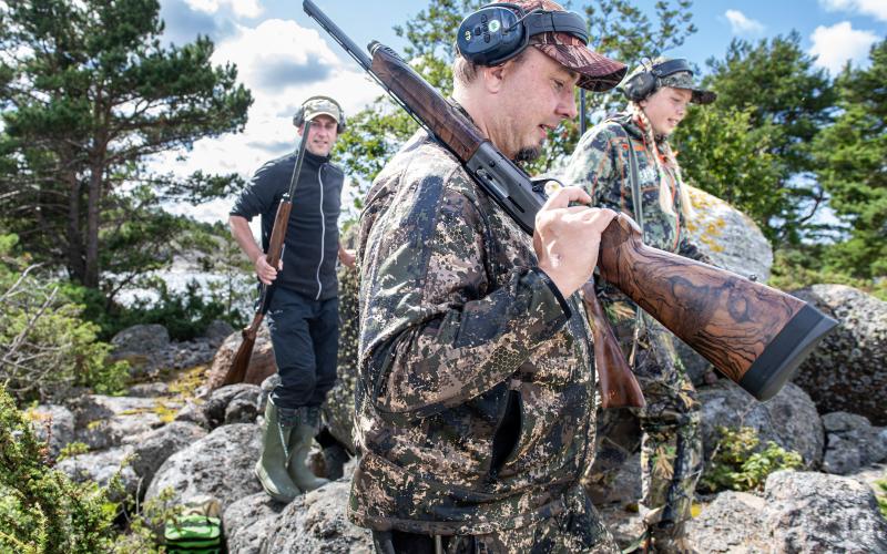 Tomas Randström, Hjalmar Hampf och Leona Hampf traskar mot stranden i jaktkläderna.