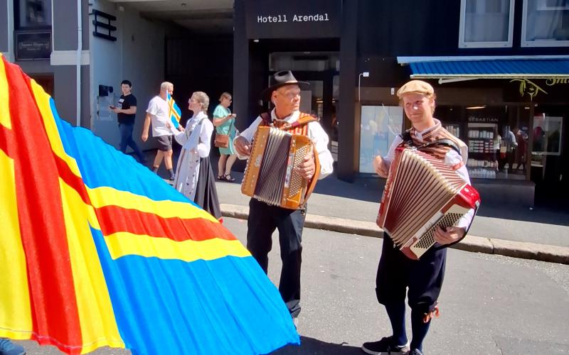 Spelmännen Martin Staaf och Erik Holst spelar till festtåget med bröllopstema framför Hotell Arendal där en del av de åländska deltagarna bodde.<@Fotograf>Sofi Lindholm