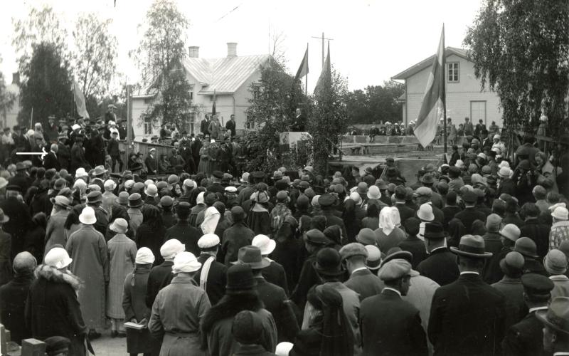 Högtidligheten då Mariehamns kyrkas grundsten lades den 4 september 1926. Mannen i den centralt placerade, flaggprydda talarstolen är biskop Max von Bondsdorff. Stadens kyrkoherde Erik Göransson ses i bildens vänstra kant, markerad med en vit pil. Han talade även vid ceremonin. 